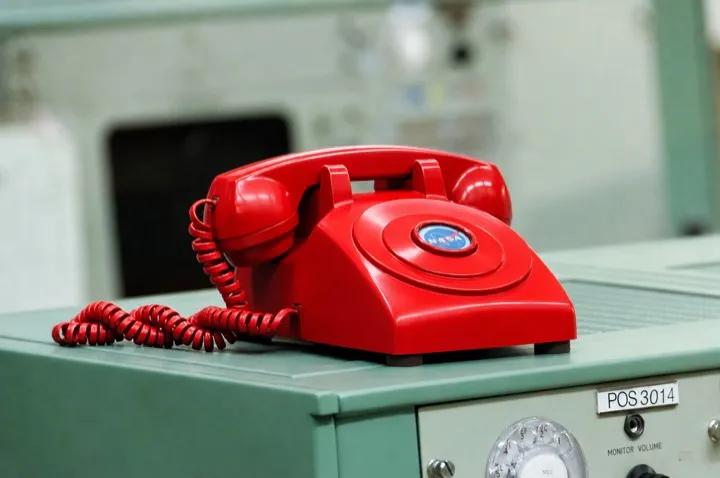 A red telephone resting on a teal Apollo-era mission control console